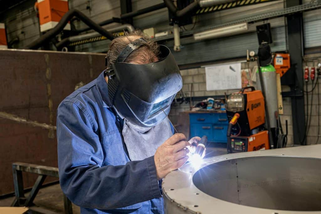 Welding inspection performed by a technician wearing protective gear in an industrial workshop.